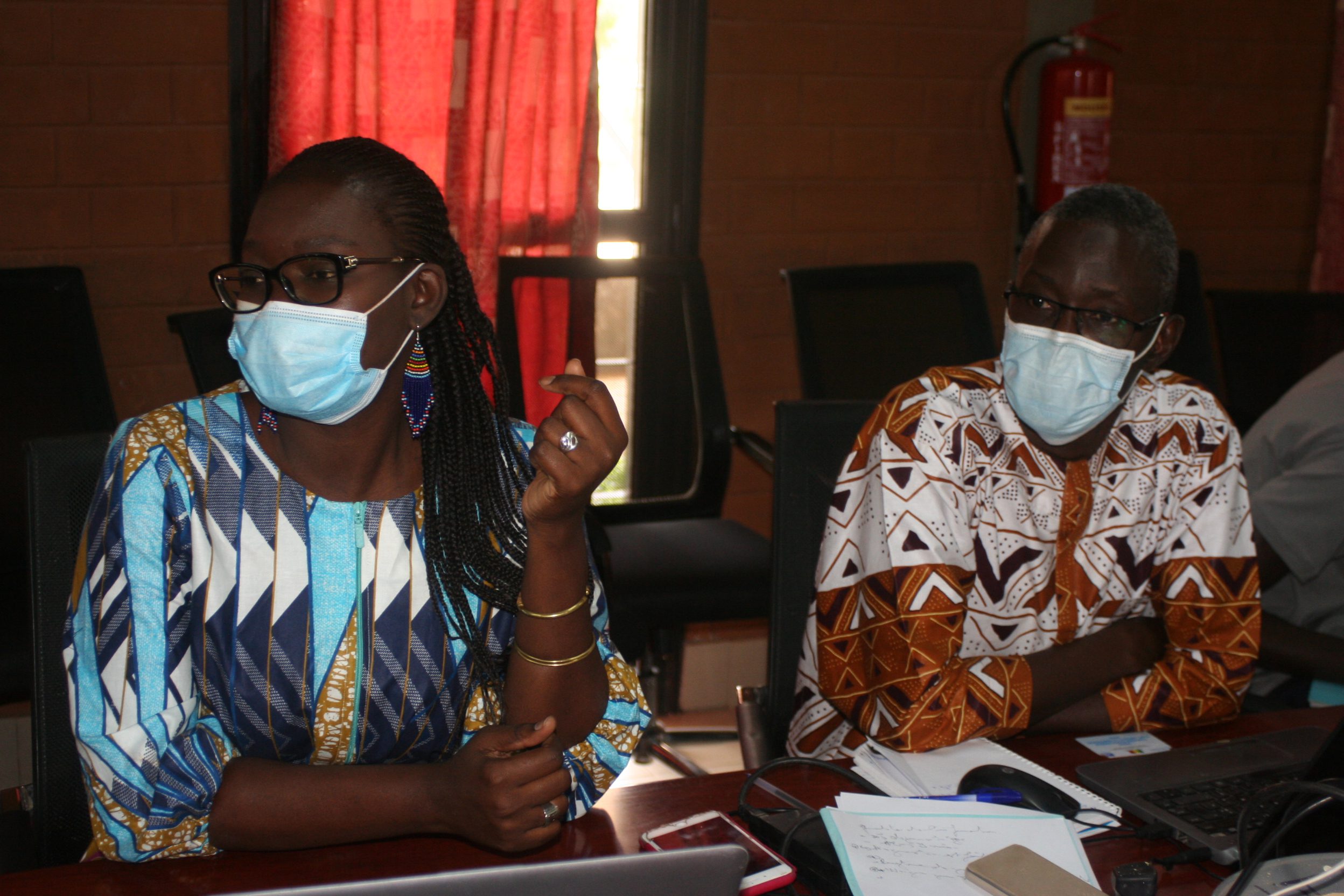 A nurse and colleague sitting at a table and wearing face masks